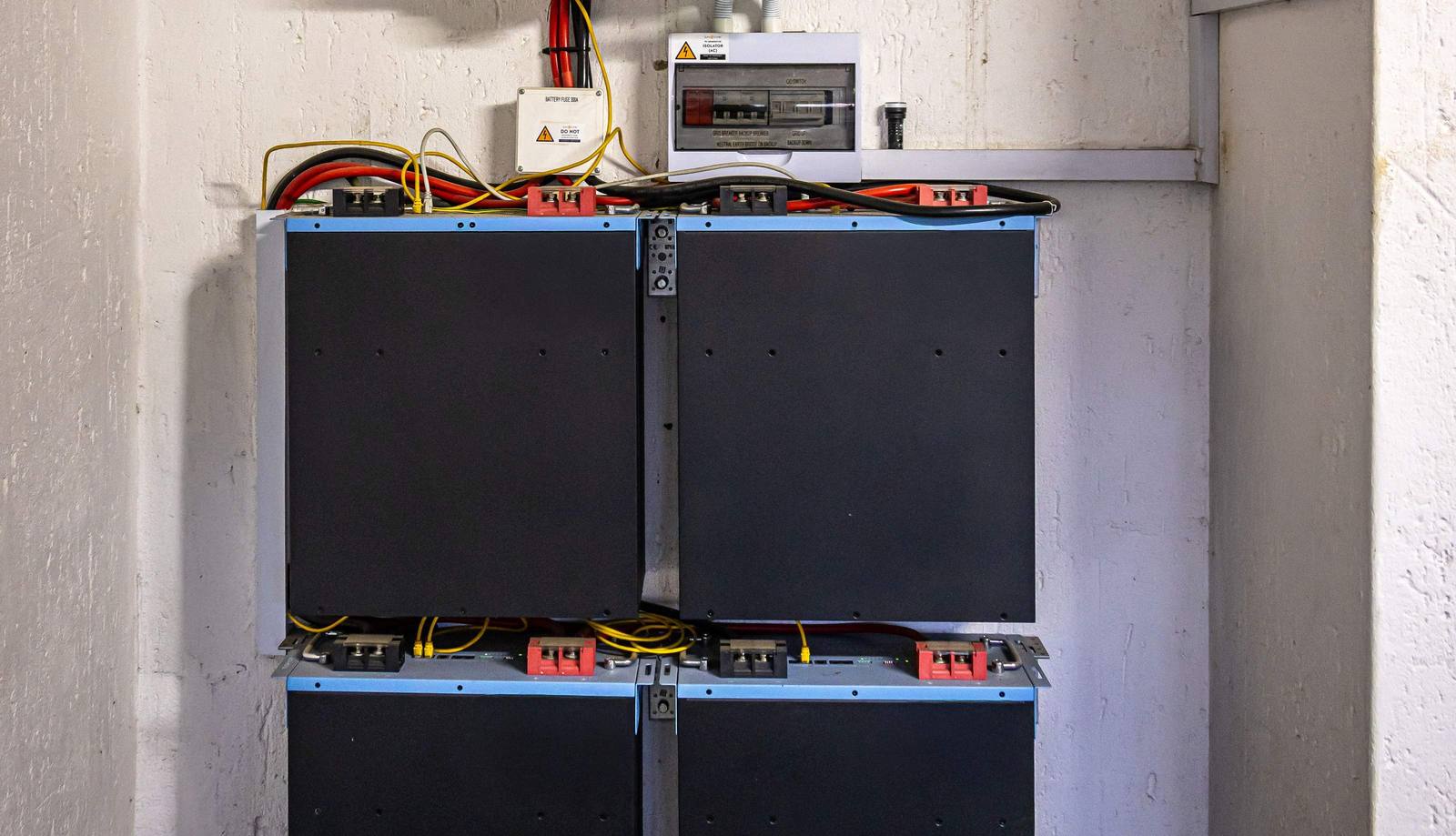 A wall-mounted home battery unit beside a standby backup generator