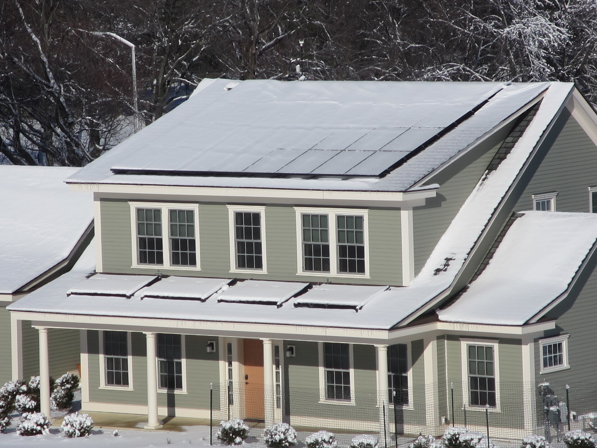 Snow lying across a residential rooftop solar array on a clear winter morning