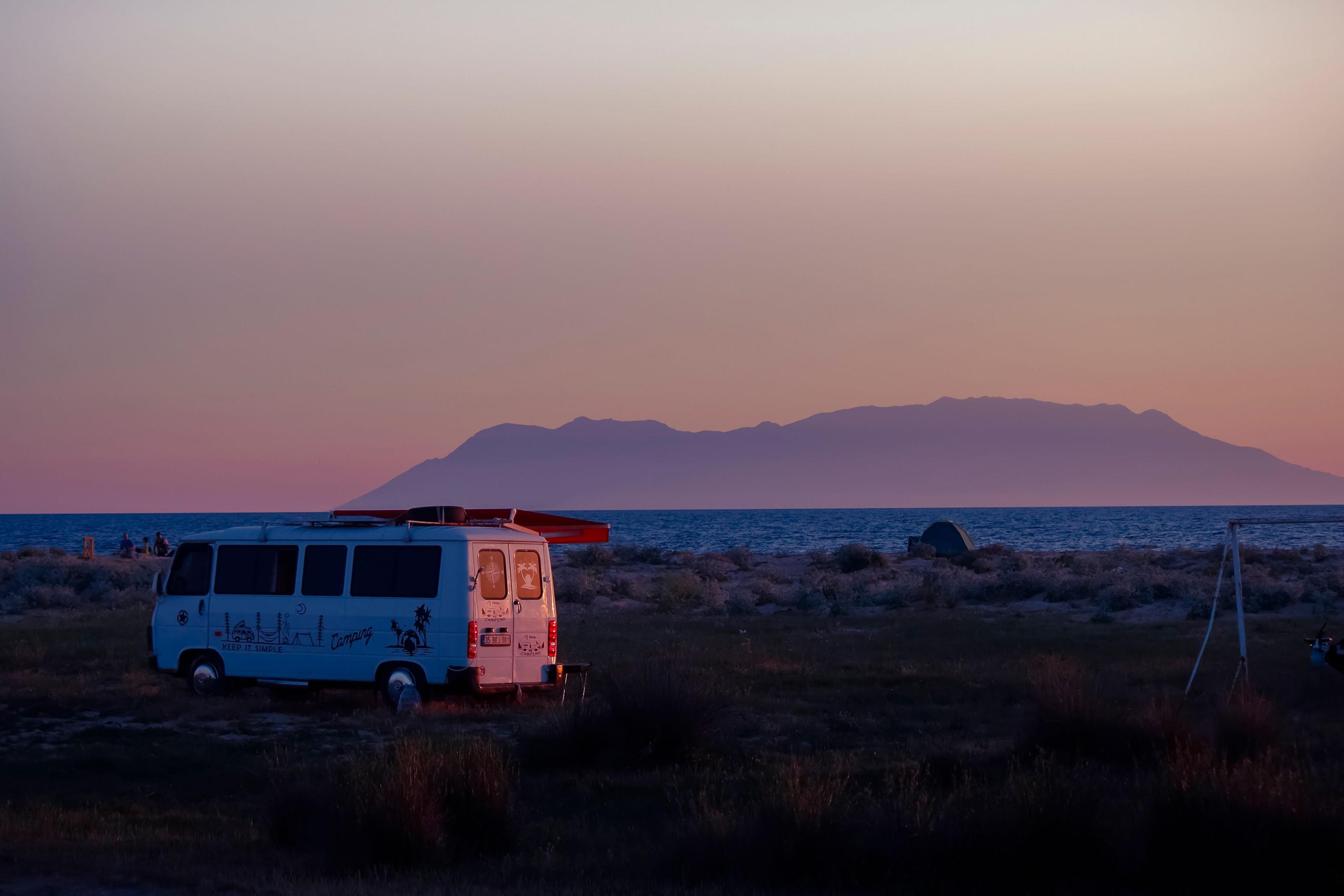 Camper van interior with a portable power station on the counter and cables running to a roof-mounted solar panel, parked on a scenic road trip pull-off