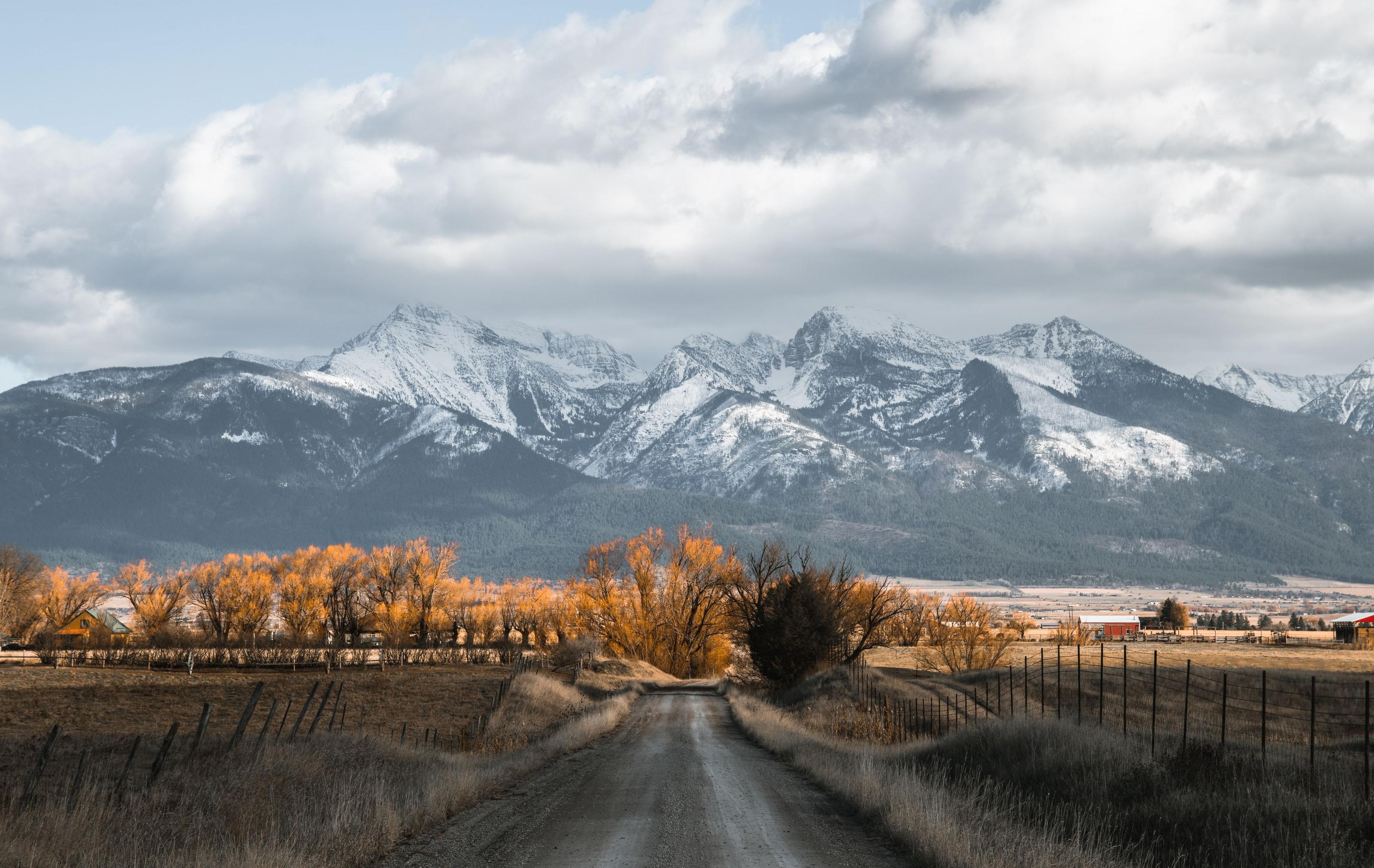 Small homestead cabin set against open rural land and distant mountains in the American West