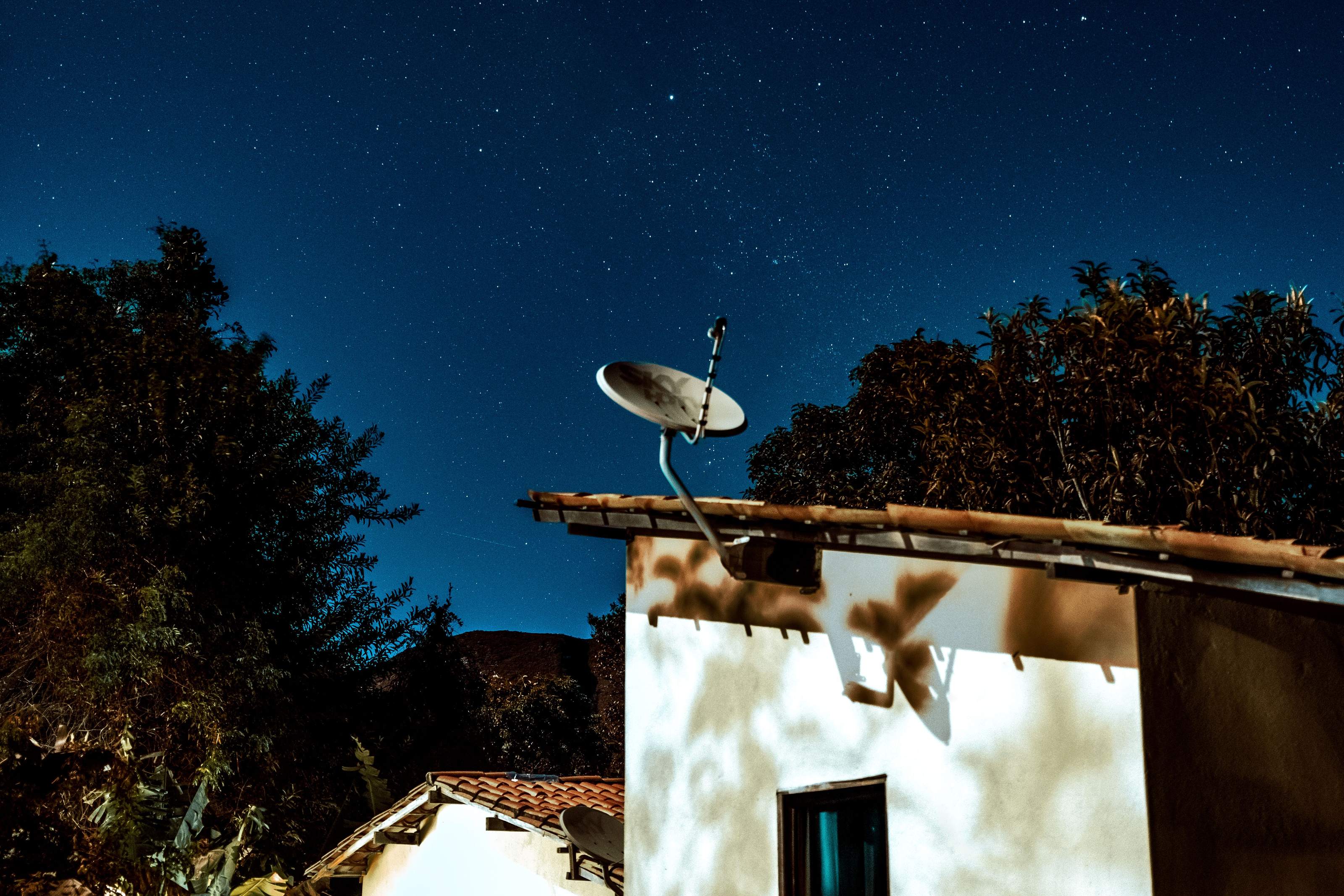 Satellite internet dish mounted on a pole beside a rural off-grid homestead