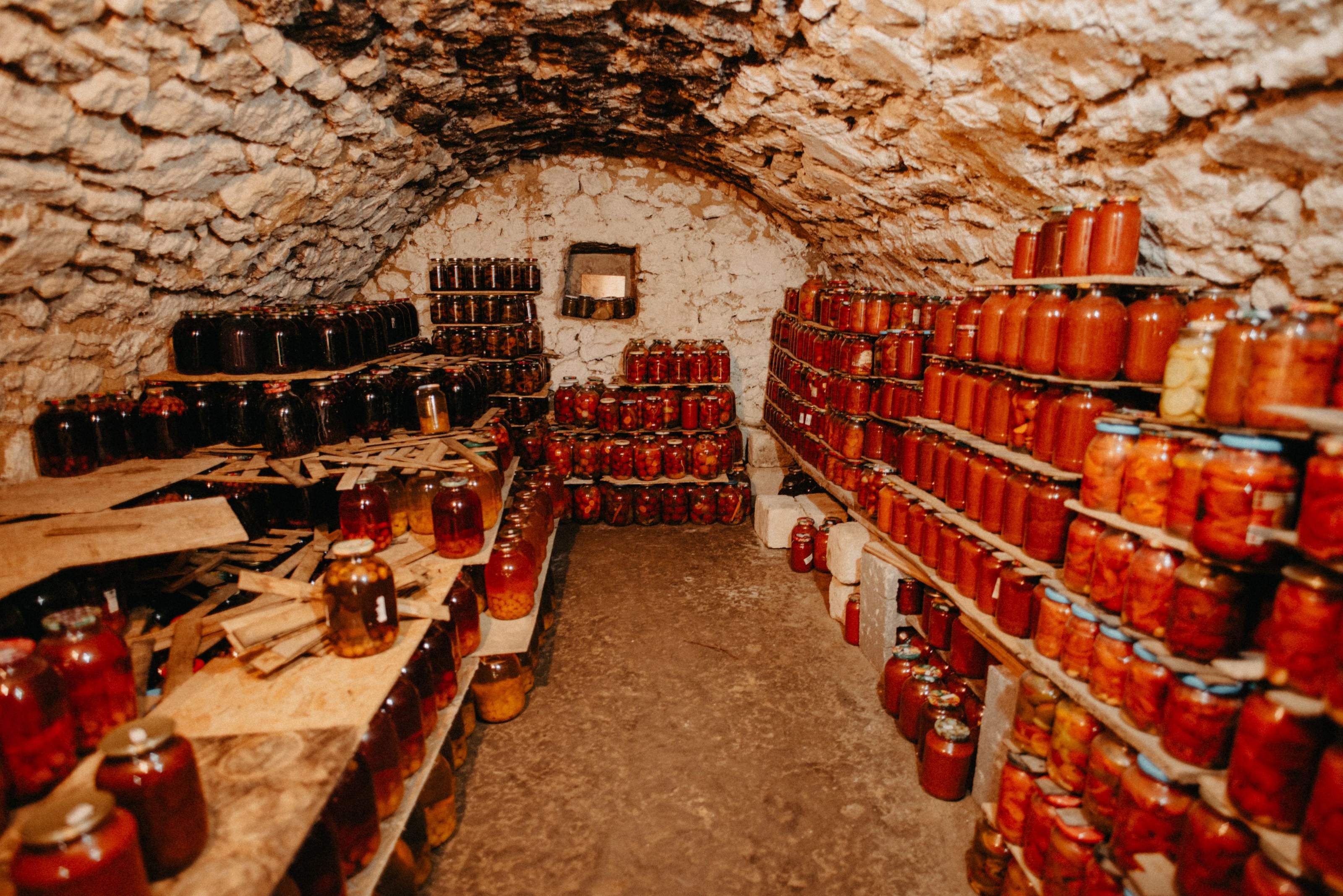 Rows of home-canned mason jars filled with preserved food on wooden pantry shelves