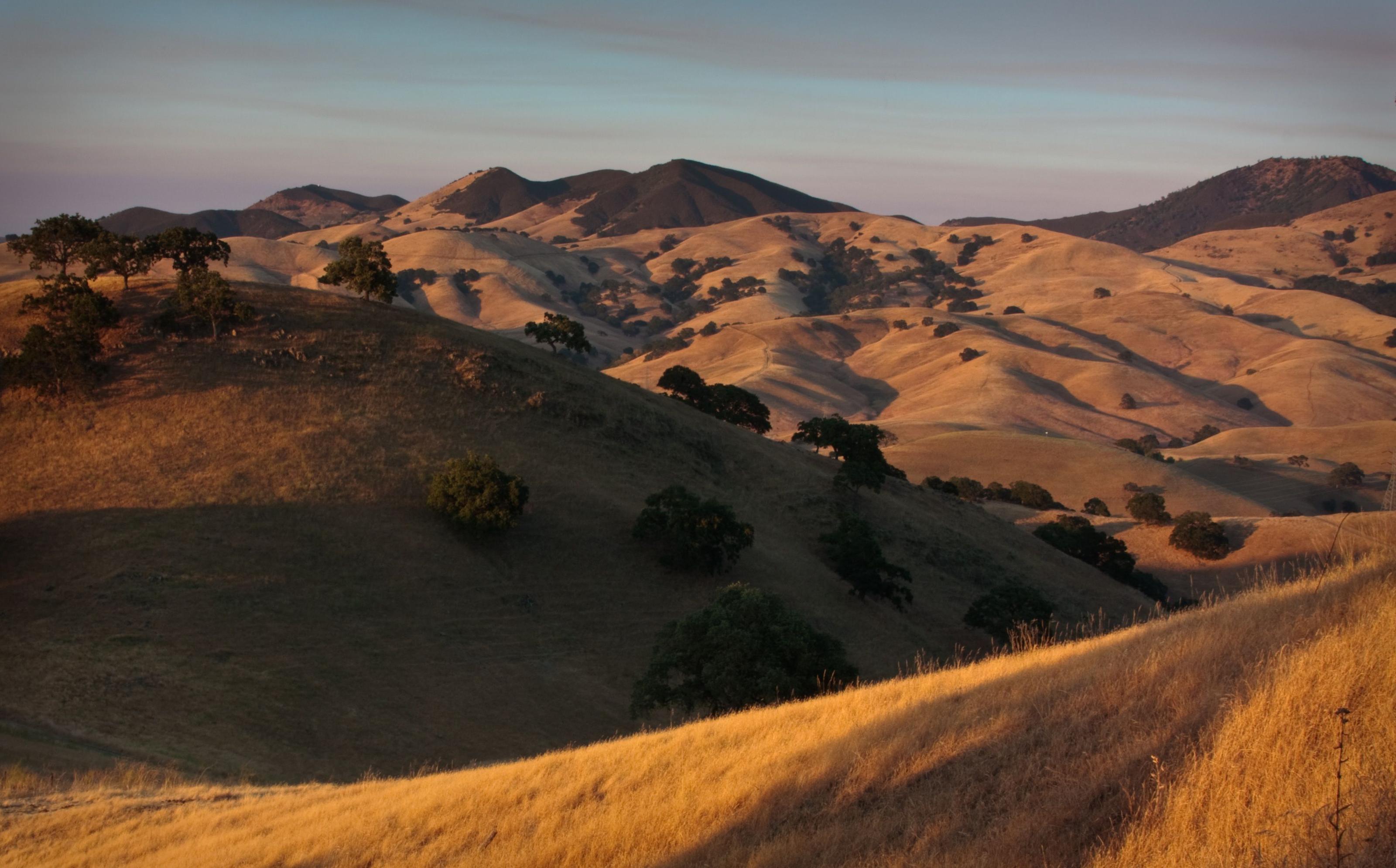 Solar-panel-dotted hills above a California home, dry wildfire-country terrain in the distance