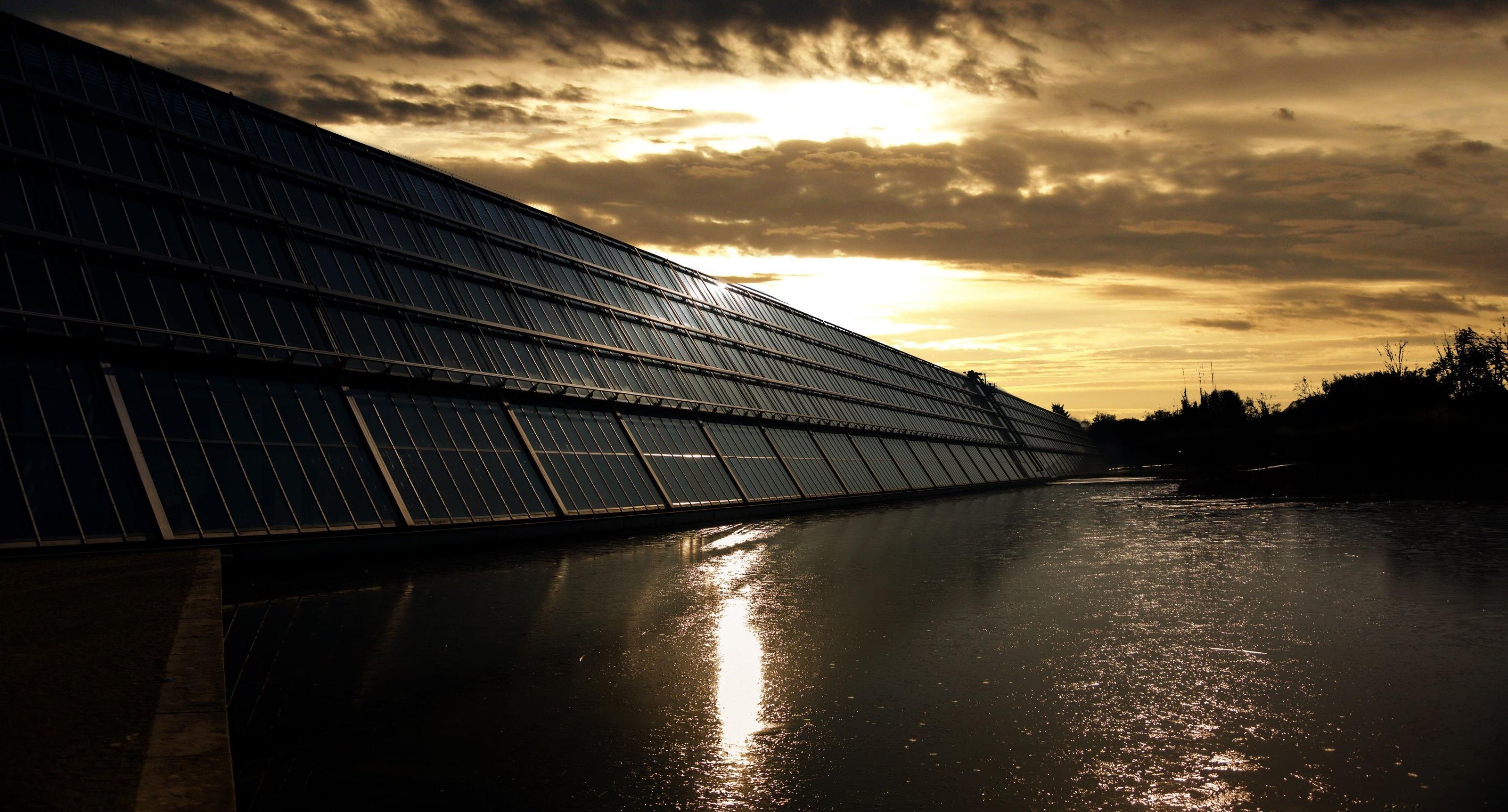 Stacks of coins arranged in ascending steps beside a small solar panel, symbolizing off-grid solar return on investment