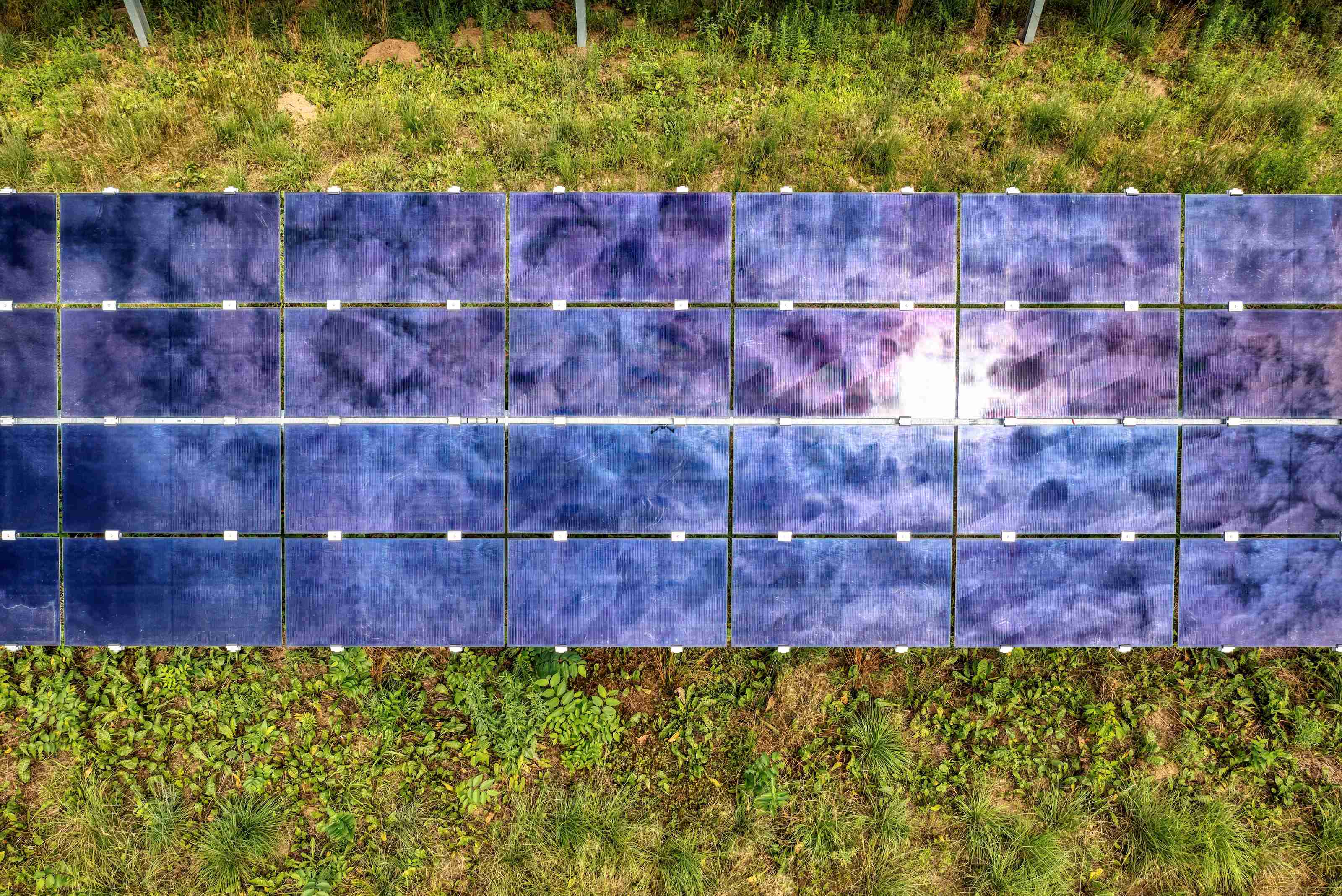 Portable foldable solar panel unfolded outdoors in direct sunlight, cable running toward a power station