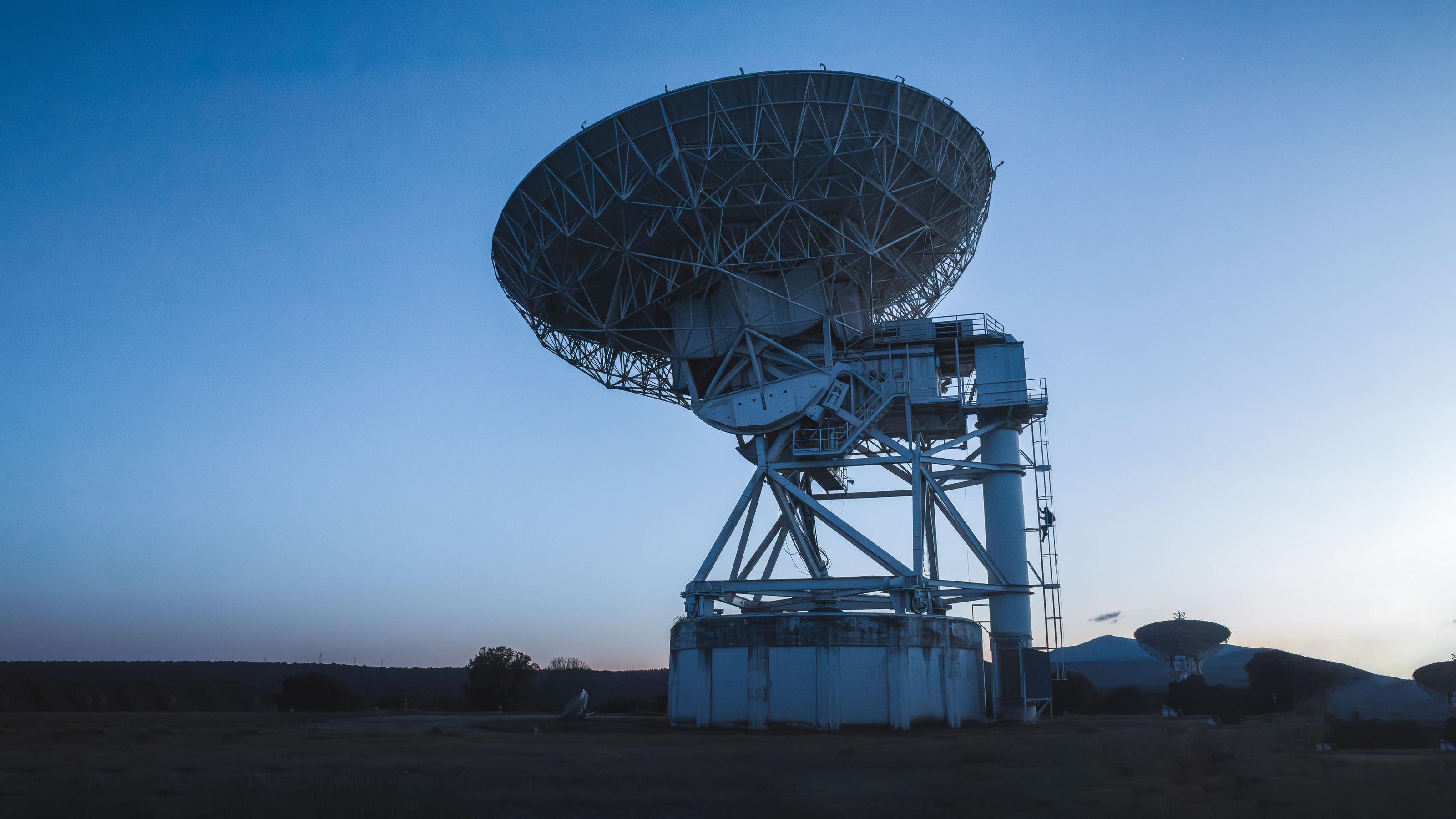A white Starlink satellite dish mounted on a rural rooftop against an open sky