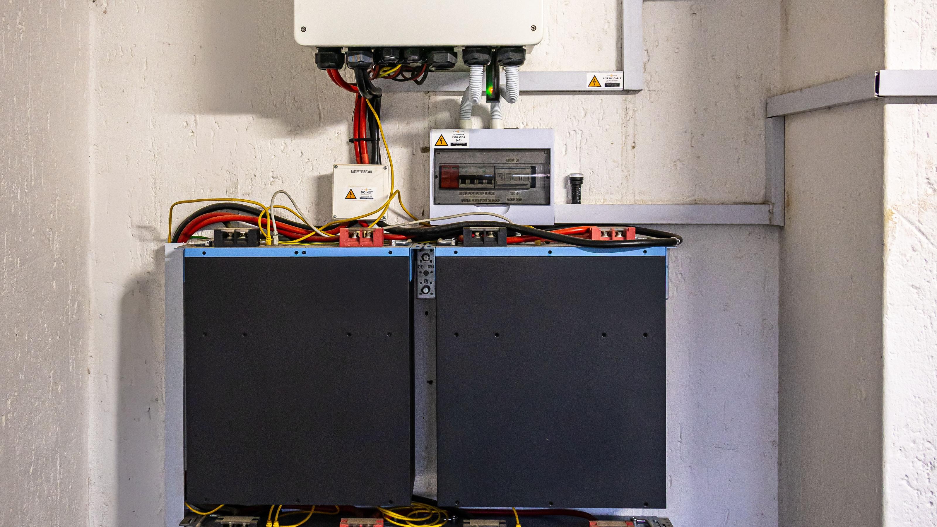 Wall-mounted lithium battery bank wired into an off-grid power room