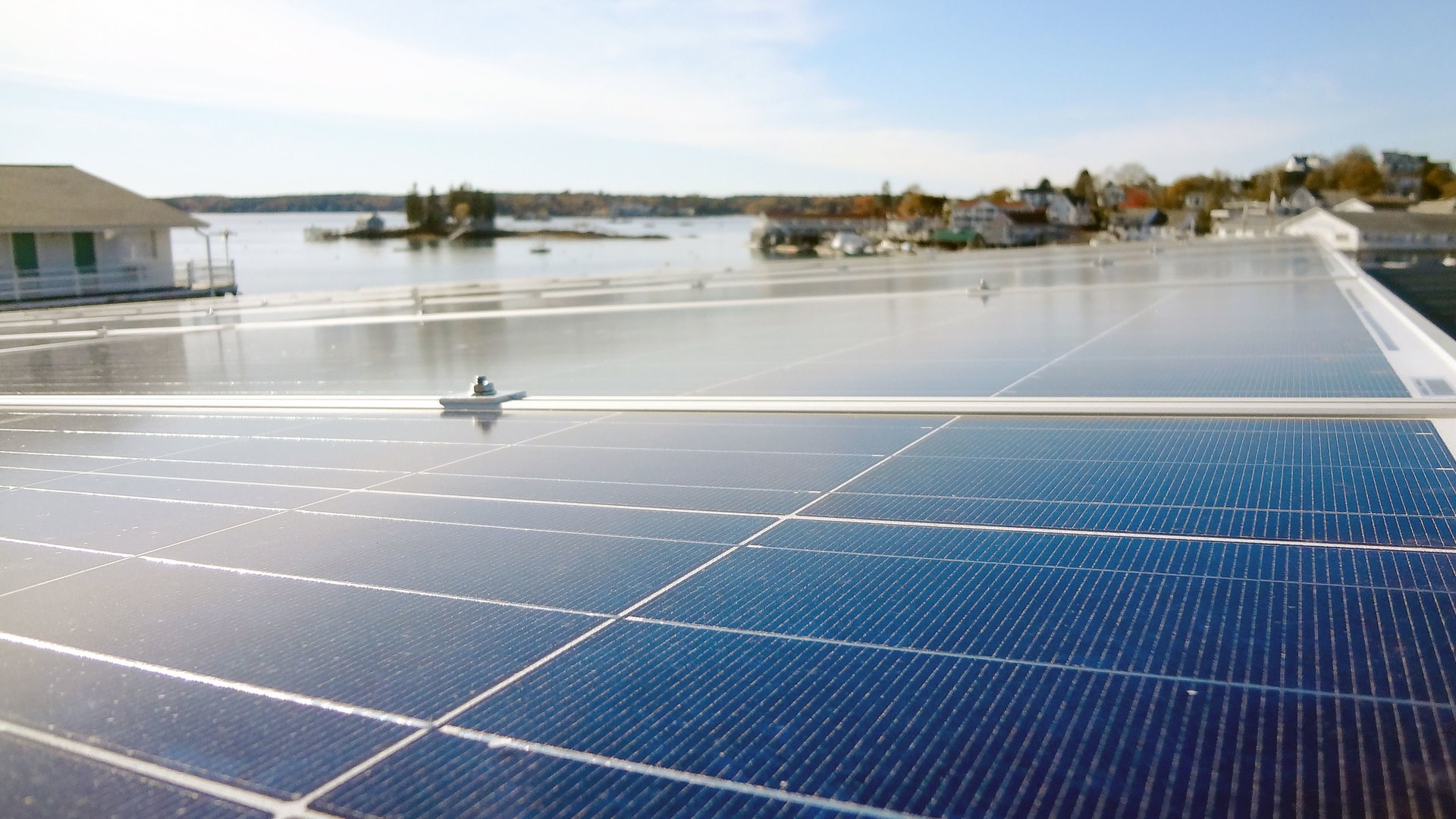 Close-up of a rooftop solar array, sunlight glancing off the glass of the nearest module